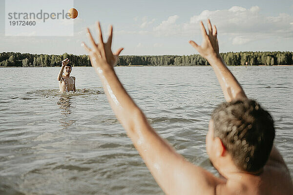 Glücklicher Vater und Sohn genießen und spielen mit dem Ball im Meer