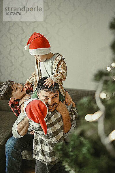 Lächelnder Vater und Söhne feiern Weihnachten zu Hause