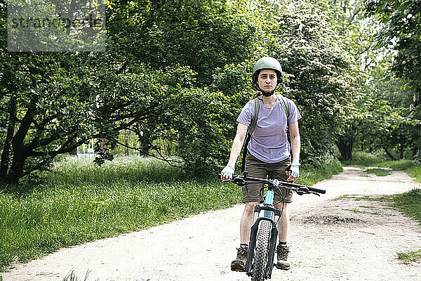 Frau fährt Fahrrad auf Fußweg im Wald