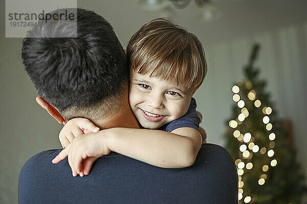 Father embracing smiling son at home
