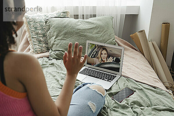 Mädchen winkt bei Videoanruf mit Freundin auf Laptop