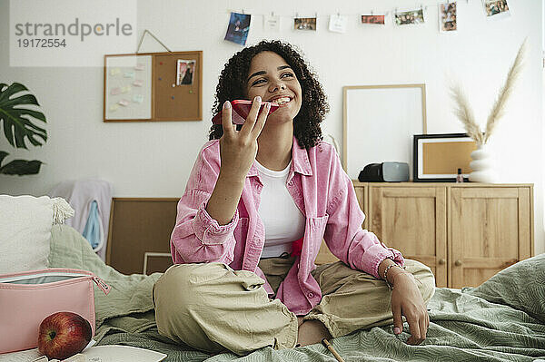 Happy girl sending voicemail through smart phone at home