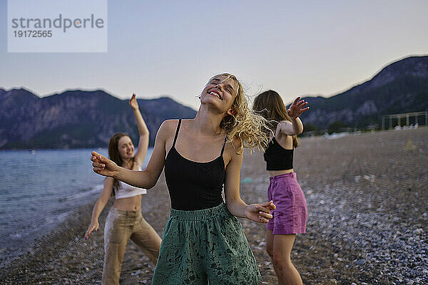 Sorglose Freunde tanzen im Urlaub am Strand