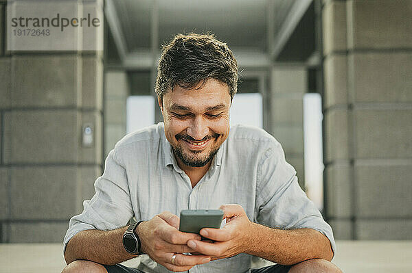 Lächelnder Mann  der Smartphone benutzt