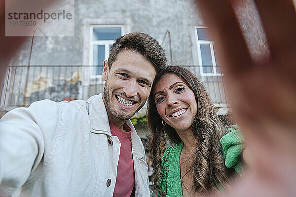 Glückliches Paar macht Selfie vor dem Haus