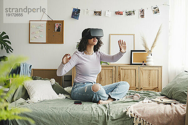 Mädchen mit Virtual-Reality-Simulatoren gestikuliert zu Hause im Bett