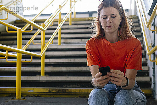 Frau sitzt auf Stufen und benutzt Smartphone