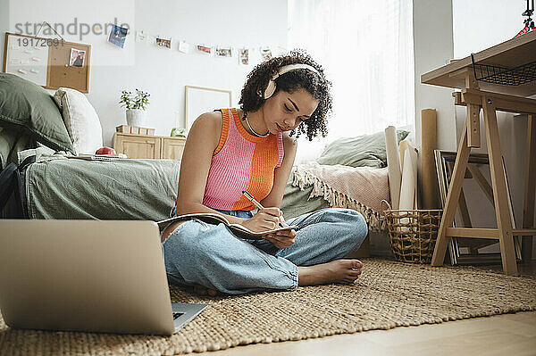 Teenage girl doing homework sitting on rug at home