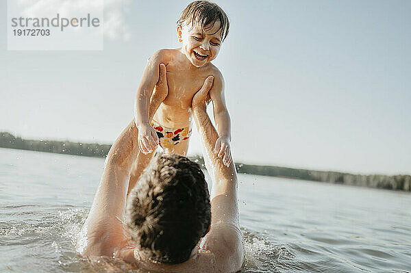 Fröhlicher Sohn genießt an einem sonnigen Tag mit seinem Vater das Wasser