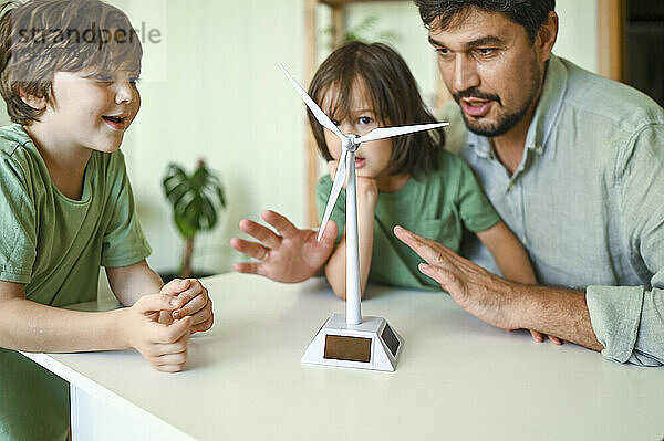 Vater und Söhne untersuchen zu Hause das Modell einer Windkraftanlage