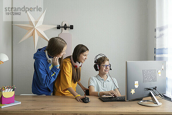 Lächelnder Junge  der zu Hause von Freunden ein Videospiel am Computer spielt