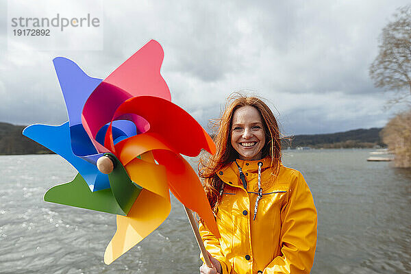 Smiling woman with pinwheel toy by lake