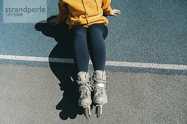 Frau mit Rollschuhen sitzt am Sportplatz