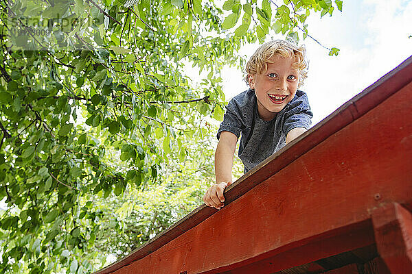 Fröhlicher Junge auf dem Dach des Spielplatzhauses