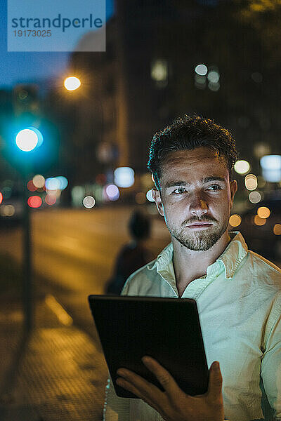 Junger Geschäftsmann mit Tablet-PC auf der Straße in der Abenddämmerung