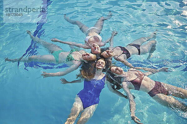 Fröhliche Freunde schwimmen zusammen und genießen im Pool