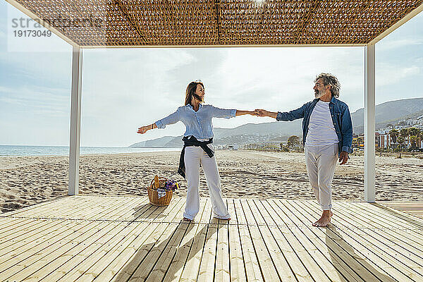 Glückliche Männer und Frauen halten Händchen und tanzen am Strand