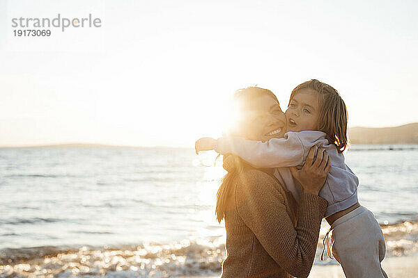 Tochter umarmt Mutter auf dem Seeweg am Strand