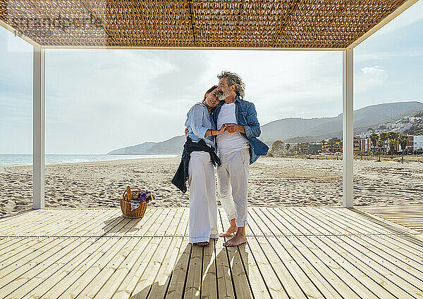 Glückliches älteres Paar umarmt sich am Wochenende im Pavillon am Strand