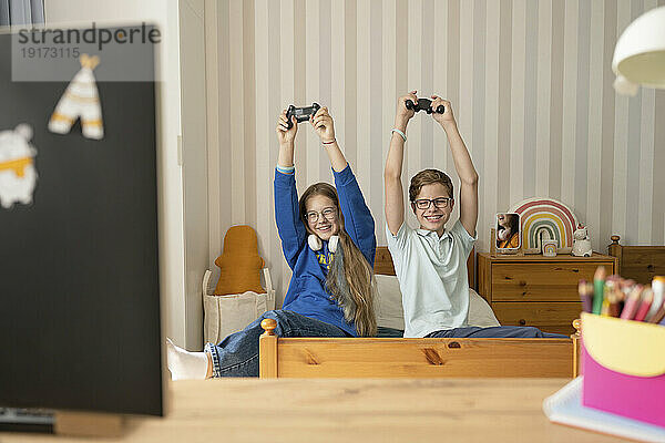 Cheerful girl and boy playing video game together at home