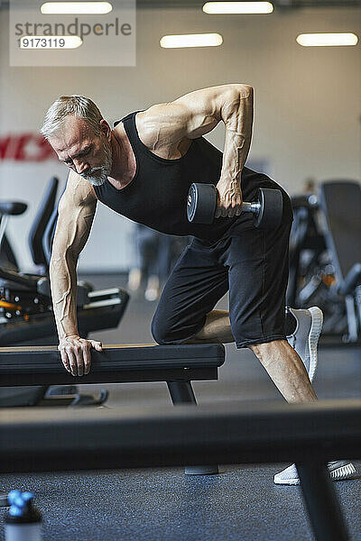 Reifer Mann macht Krafttraining mit Hanteln im Fitnessstudio