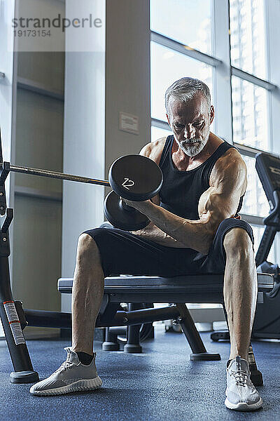 Reifer Mann macht Bizepsübungen im Fitnessstudio