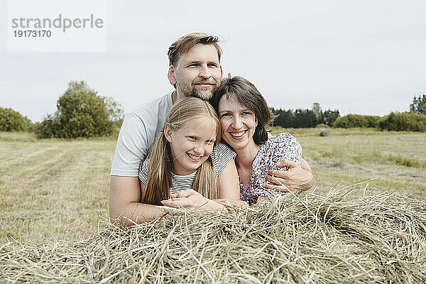 Glückliche Familie stützt sich auf Heu im Feld