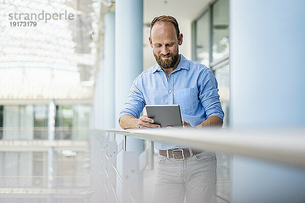 Erfahrener Geschäftsmann nutzt digitales Tablet im Bürogebäude