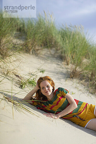 Lächelnde Frau entspannt sich im Sand am Strand