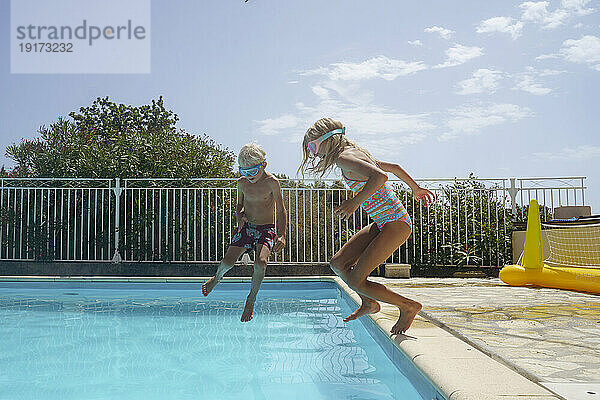 Fröhlicher Bruder und Schwester springen im Schwimmbad