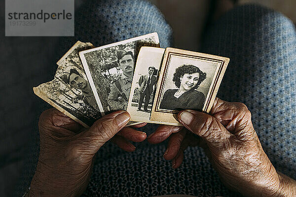 Hände einer Frau  die zu Hause Fotos aus der Vergangenheit hält