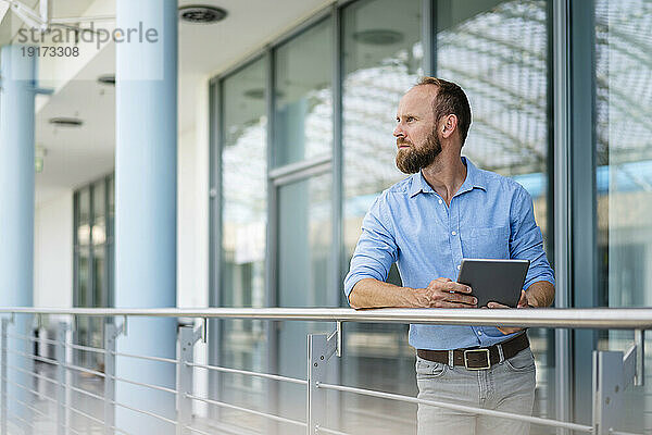 Experienced businessman using digital tablet standing in office building