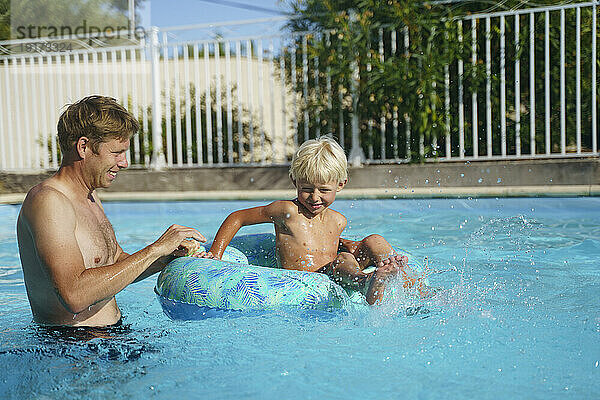 Vater spielt mit Sohn im aufblasbaren Schwimmring