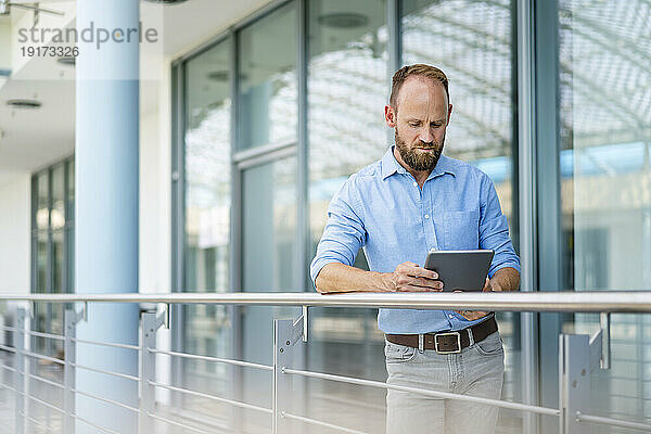 Experienced businessman using digital tablet standing in office building