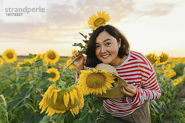 Glückliche Frau mit Hut im Sonnenblumenfeld