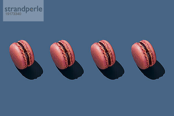 Pink macaroons arranged on blue background