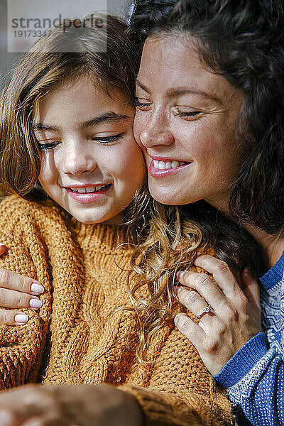 Smiling mother hugging daughter at home