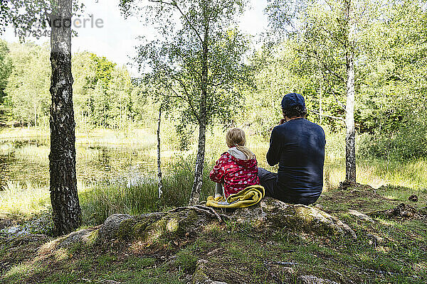 Vater und Tochter sitzen zusammen im Wald
