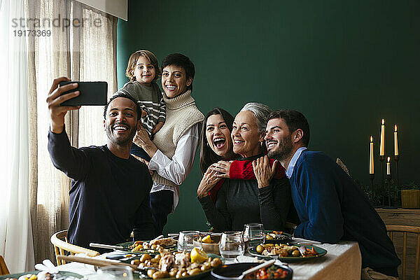 Lächelnde Familie  die zu Hause ein Selfie mit dem Smartphone macht