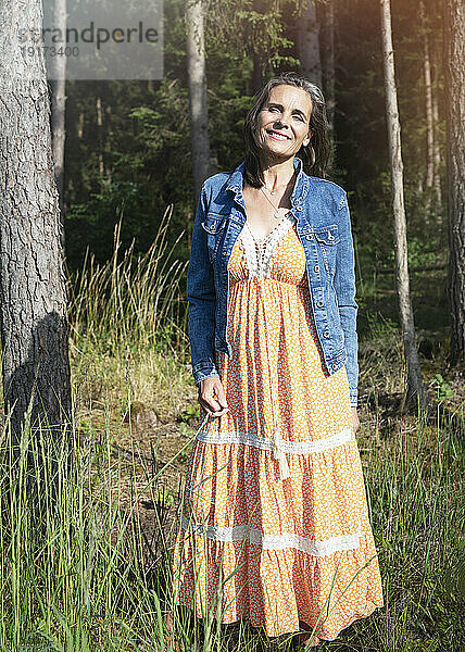 Lächelnde Frau in Jeansjacke im Sommer im Wald