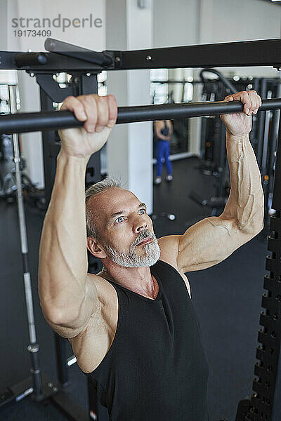 Muskulöser reifer Mann macht Klimmzüge im Fitnessstudio