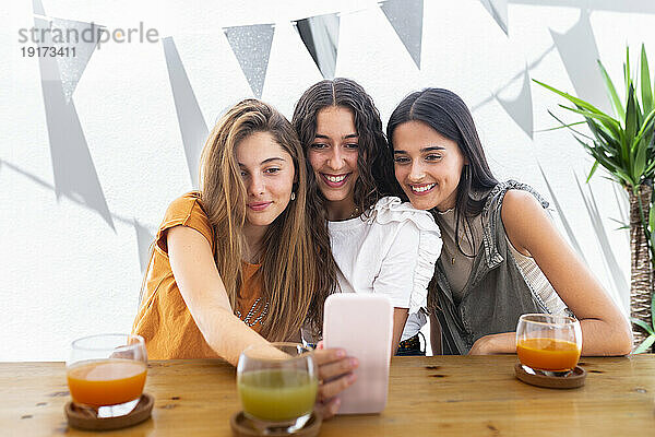 Glückliche Freunde  die am Tisch ein Selfie mit dem Smartphone machen