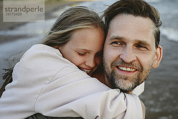Glückliche Tochter umarmt Vater am Strand