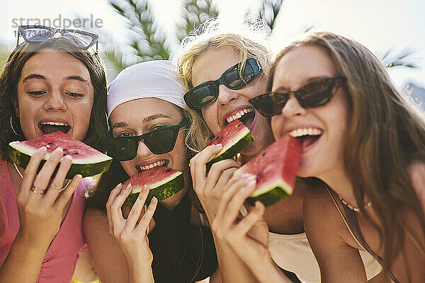 Fröhliche Freunde  die an einem sonnigen Urlaubstag Wassermelone essen