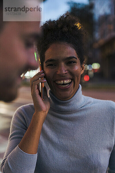 Glückliche junge Frau  die auf dem Smartphone spricht