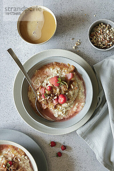 Studioaufnahme einer Schüssel veganen Porridge mit Erdbeeren  Mandeln und Rhabarberkompott