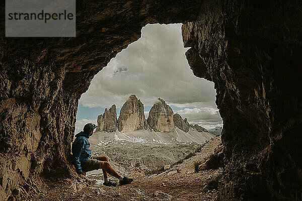 Italien  männlicher Wanderer blickt vom Höhleneingang auf die drei Zinnen von Lavaredo