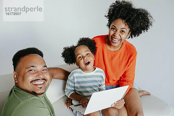 Glückliche Familie mit Laptop vor weißem Hintergrund im Studio