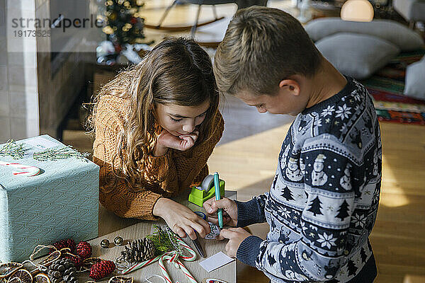 Schwester und Bruder schreiben zu Hause eine Notiz in der Nähe einer Geschenkbox