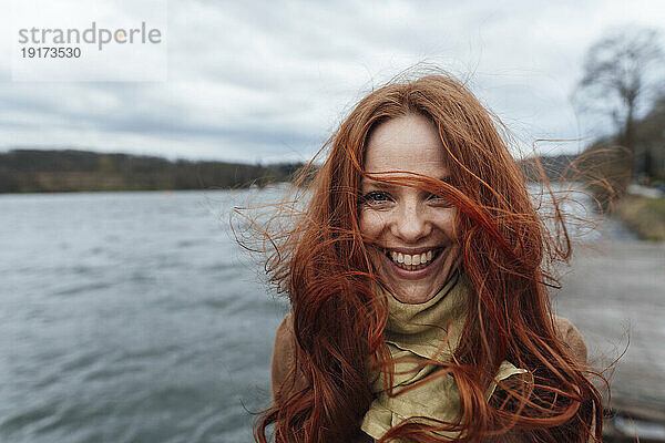 Redhead woman laughing and enjoying in front of lake